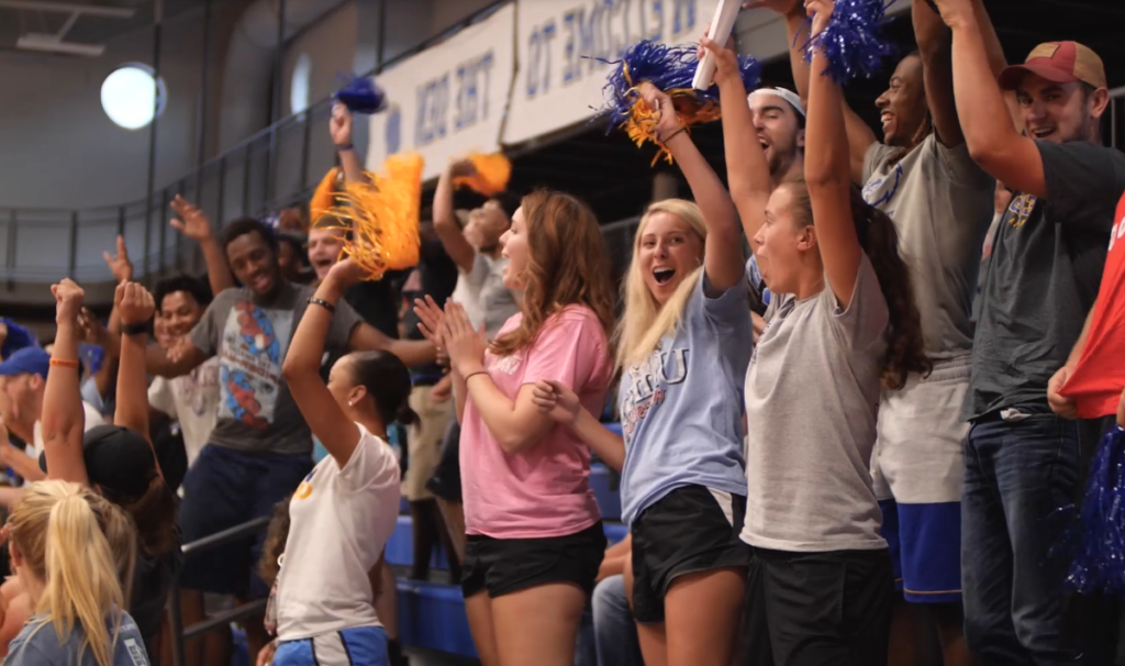 Group of 学生 cheering at a game inside of the gym in the Moore Center.